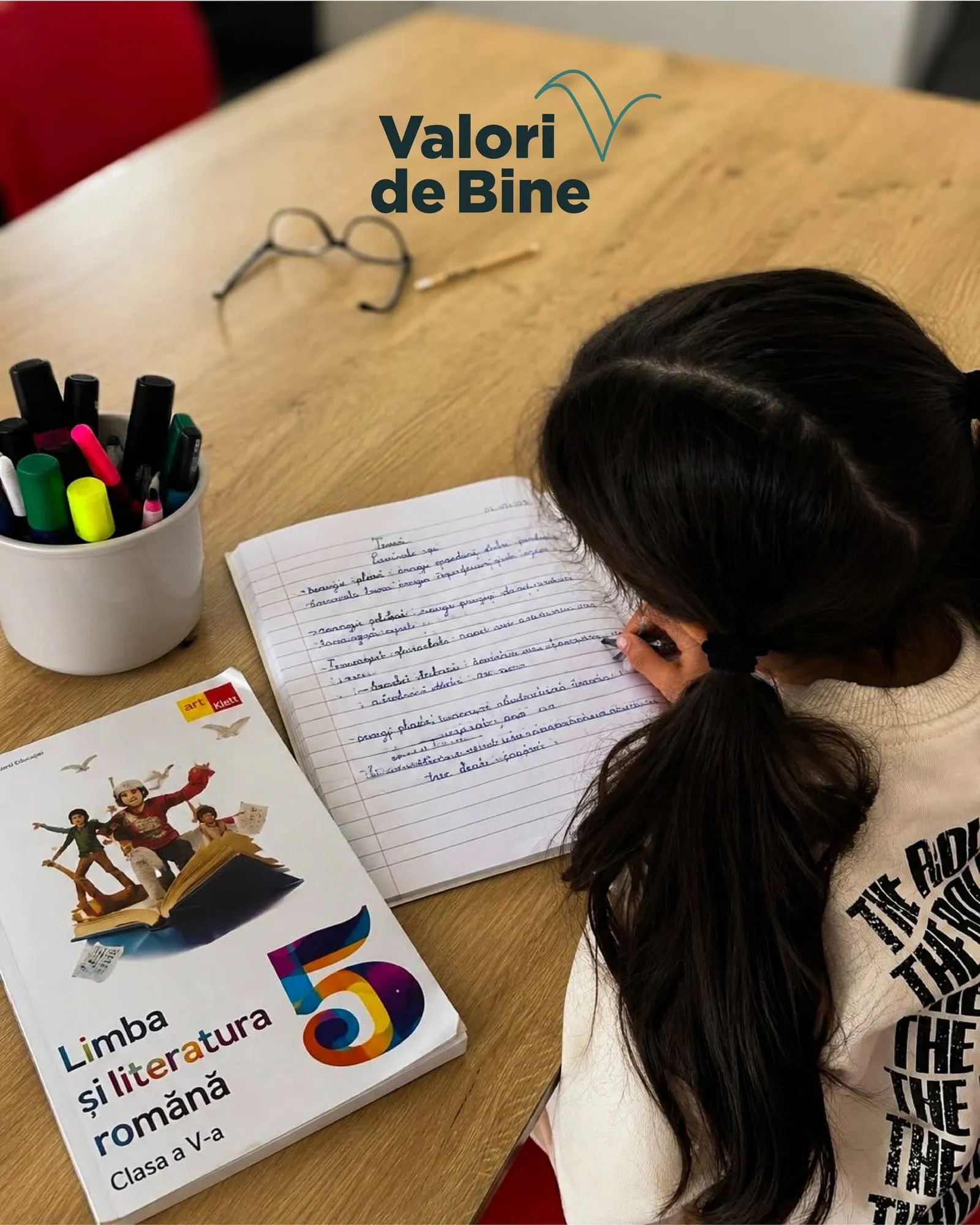 Copil care scrie într-un caiet la o sesiune de sprijin educațional